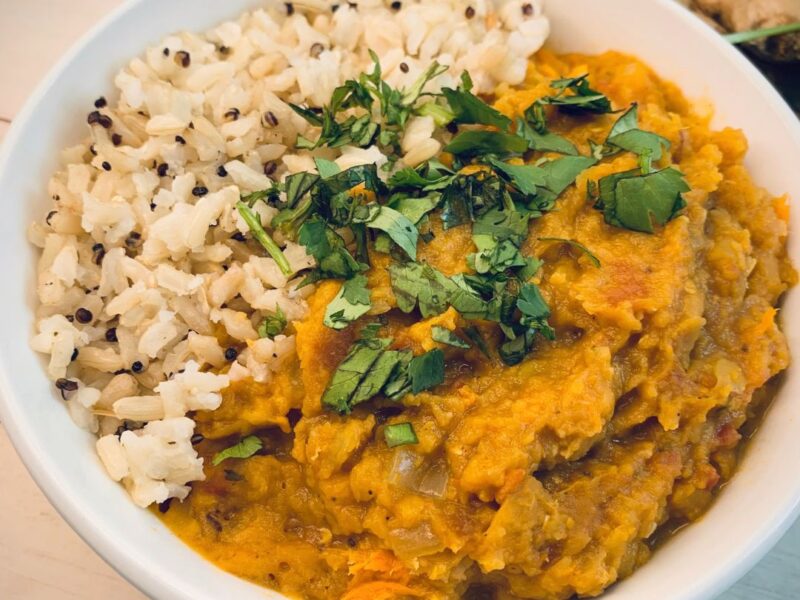 bowl of red lentil curry with rice and cilantro